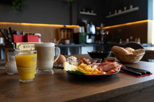 Nahaufnahme von einem gedeckten Frühstückstisch mit Orangensaft, Kaffeespezialitäten und frischen, cremigen Rührei.